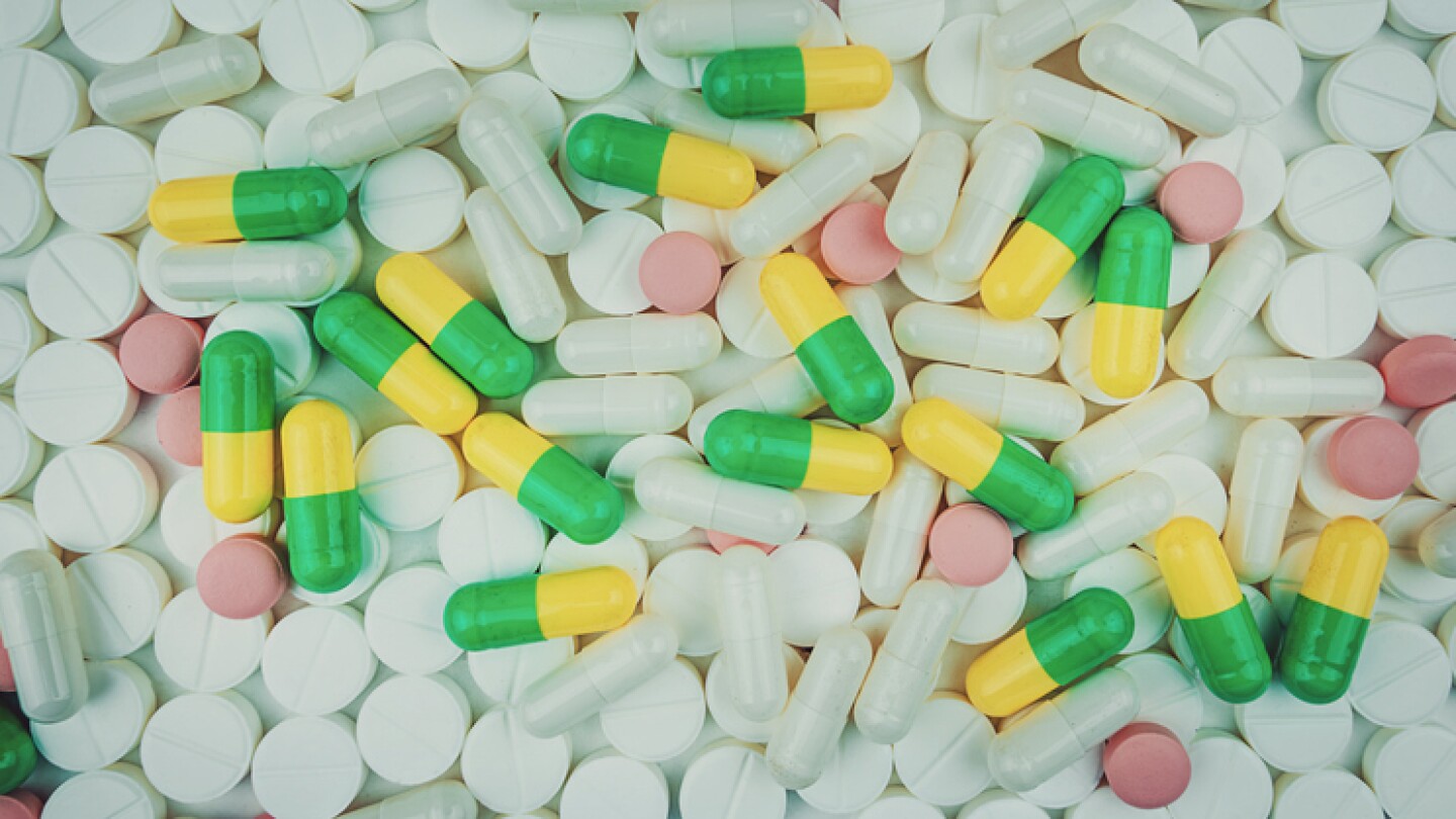 White and multi colored pills on white background top view