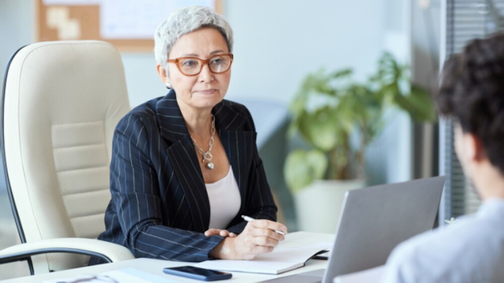 Two people talking in an office/iStock, SeventyFou