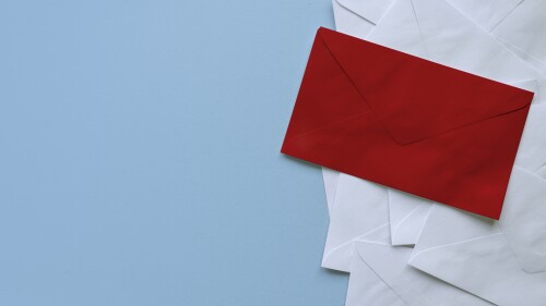 A stack of white envelopes with a red envelope on top. Blue background with copy space.
