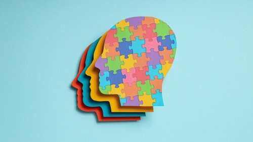 Paper human heads with colorful puzzle pieces on a light background. World autism day concept
