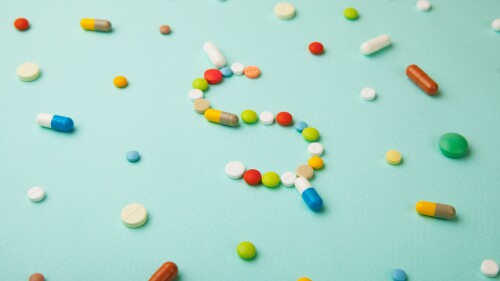 Symbol of money dollar from colored pills and capsules on green background. Expensive medicine and medical insurance