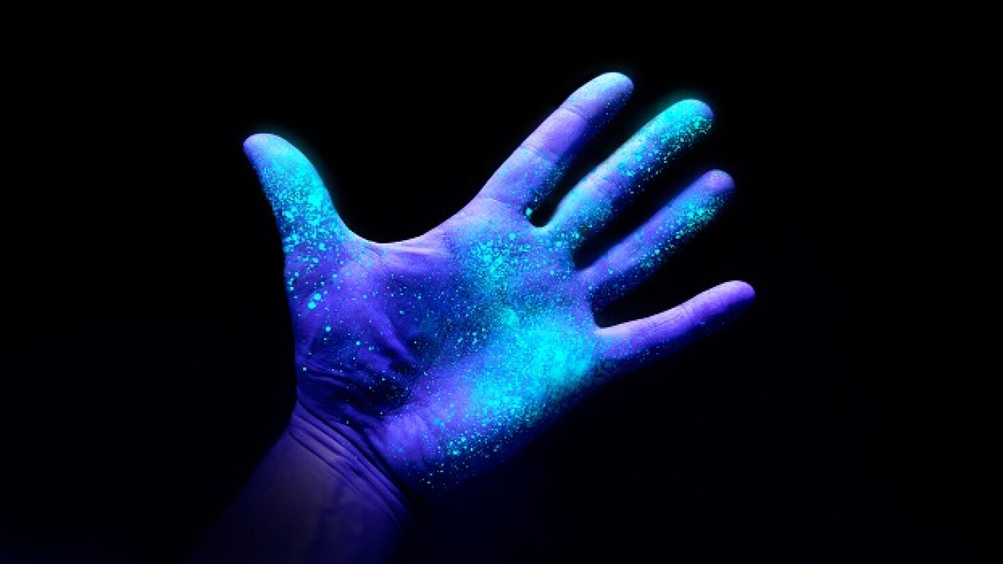 UV Ultraviolet light on a hand illustrating the effect of bacteria and viruses on asurface that has not been washed showing the importance of good hygiene and hand washing espically during a pandemic such as Covid-19.