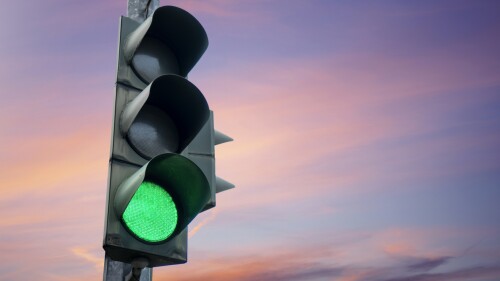 Traffic light in green color, with the dusk sky in the background.