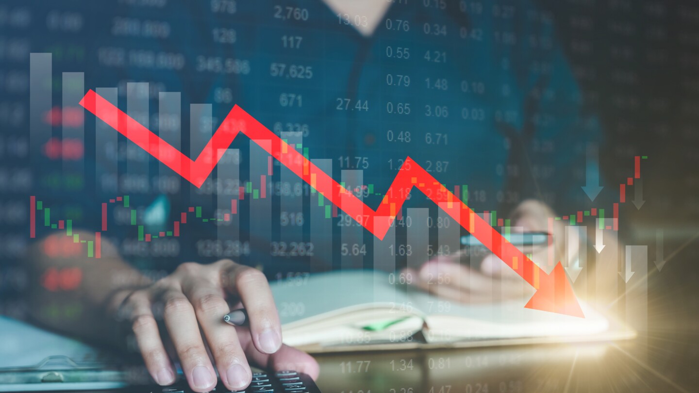 Downward trendline superimposed on a picture of a man working on financial records