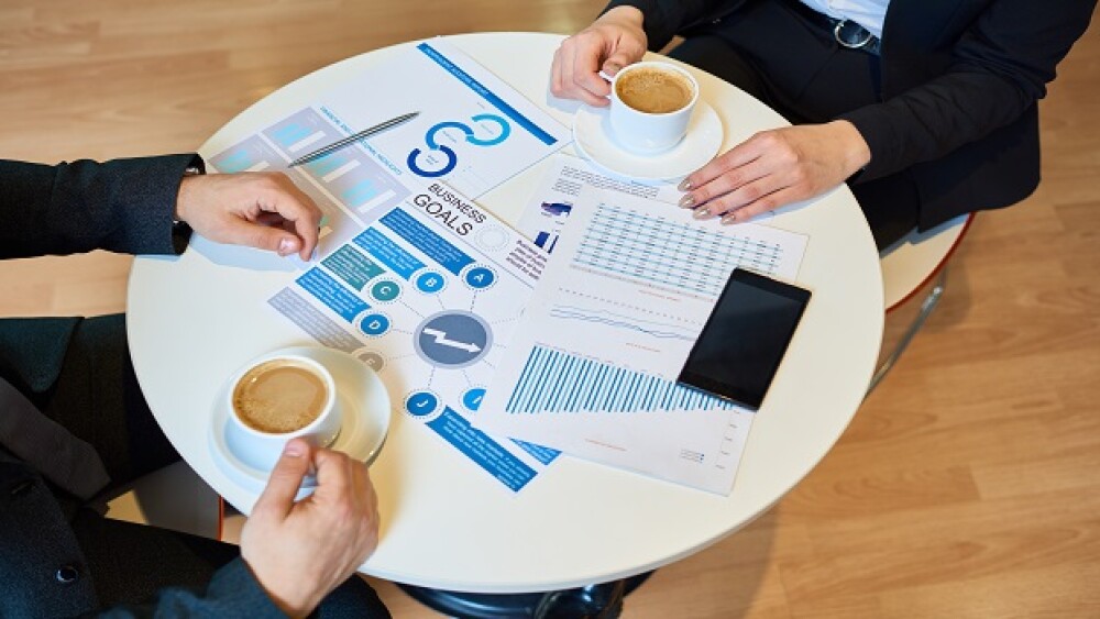 Close-up of unrecognizable business partners discussing business goals and collaboration over coffee