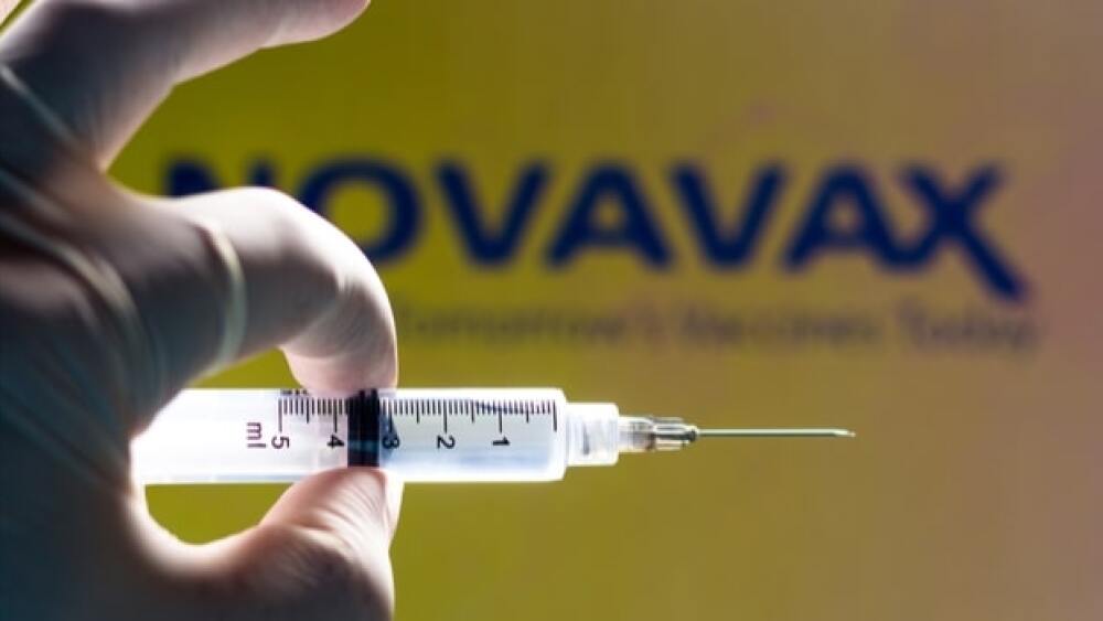 Pictured: Gloved hand holding syringe in front of