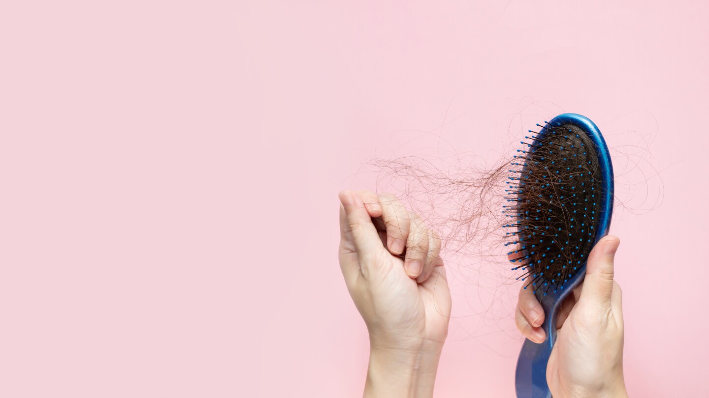 woman hand is removing hair from blue brush. A Hair care.