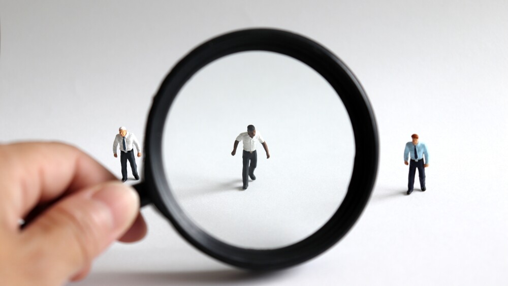 A concept of unfair social prejudice. The miniature men and a magnifying glass.