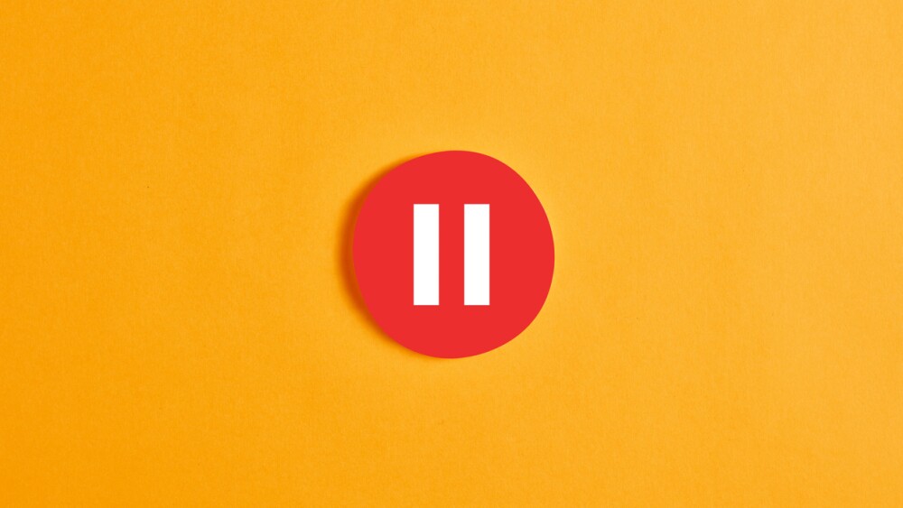 Red round circle with a pause button or icon against yellow background.