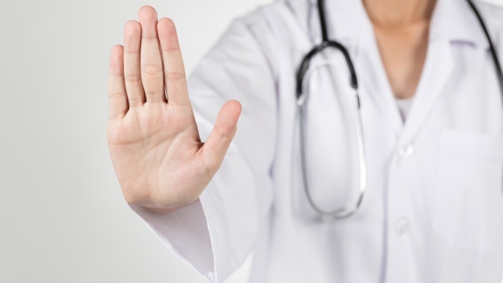 Physician holds up hand in a stop sign signal_Shut