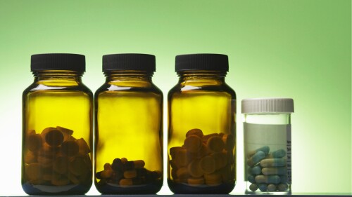Close-Up Of Medicine Bottles Against Green Background