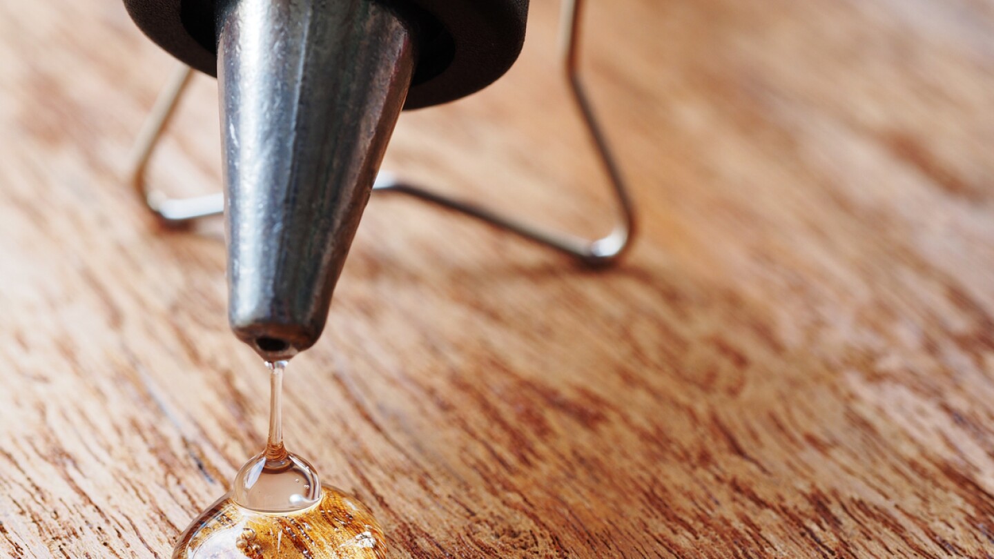 closeup hot glue gun with melted glue dripping out