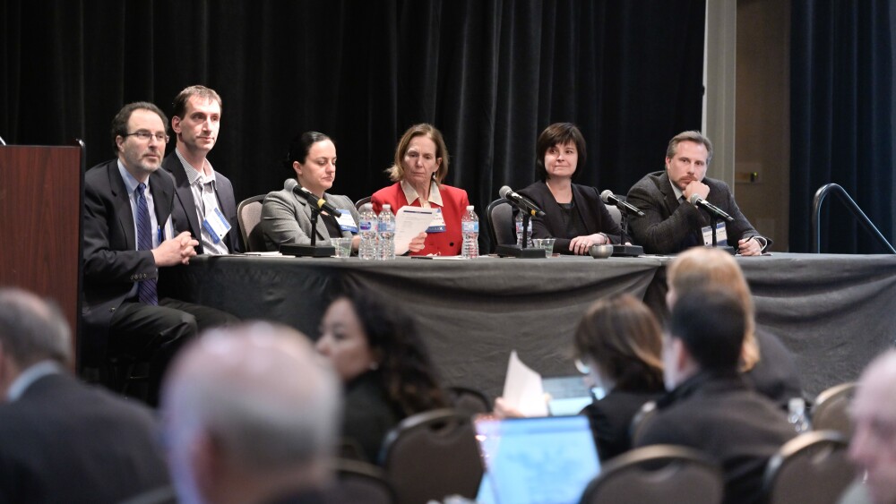 A group of people sitting before microphones at a table on a stage
