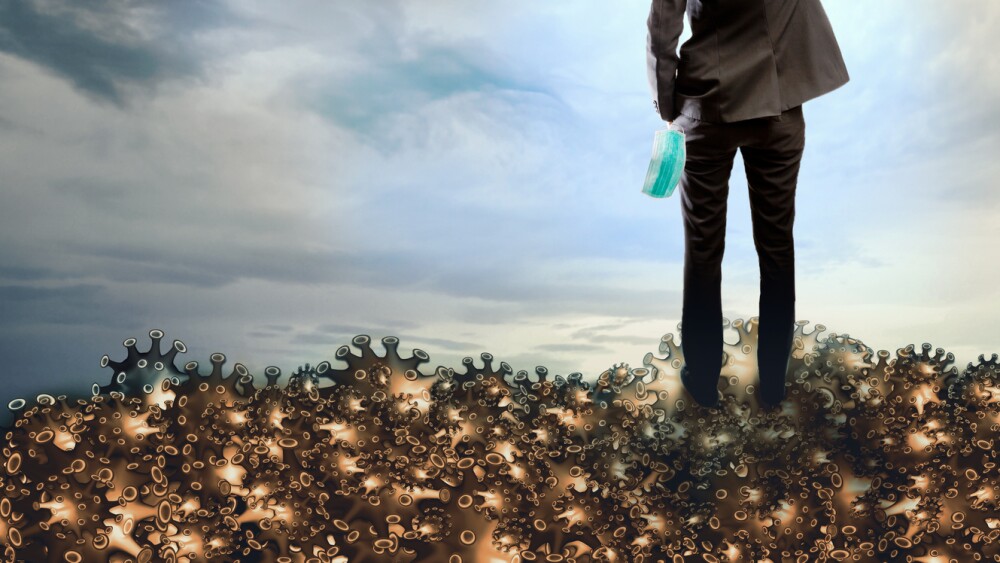 Man with medical or hygienic mask standing over dead covid 19 or Corona virus raised their hand to win the Covic-19 or Coronavirus, At last mankind will win and survive over the virus concept