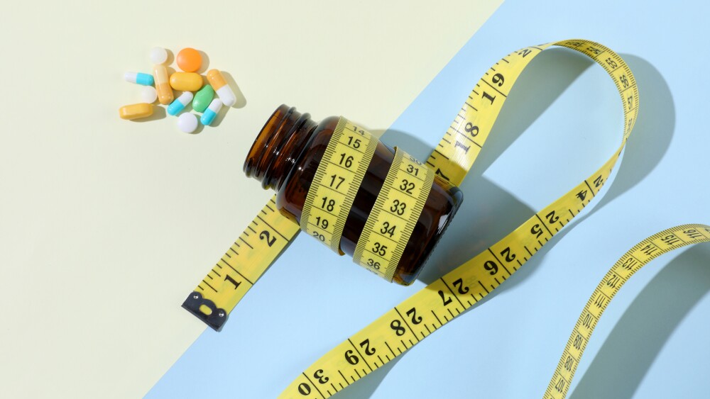 Diet pills and bottle of diet supplements with measuring tape