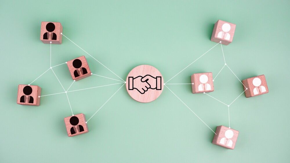 Business and HR concepts for leaders and teams. Circular wooden blocks with hand icons printed on them are connected to wooden blocks with business people icons printed on them. Teamwork concept, business concept