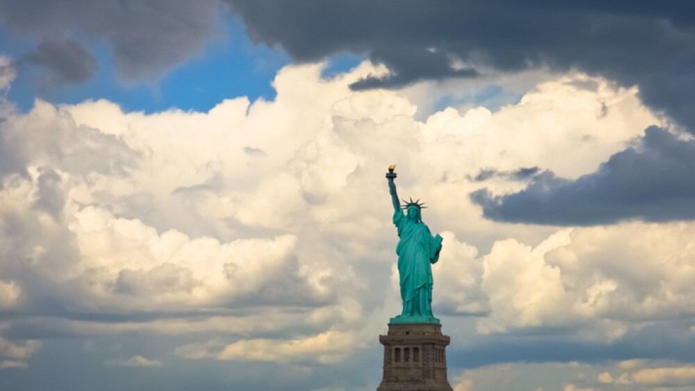 A panoramic view of the Statue of Liberty framed by heavy clouds just before storm. USA, New York City.