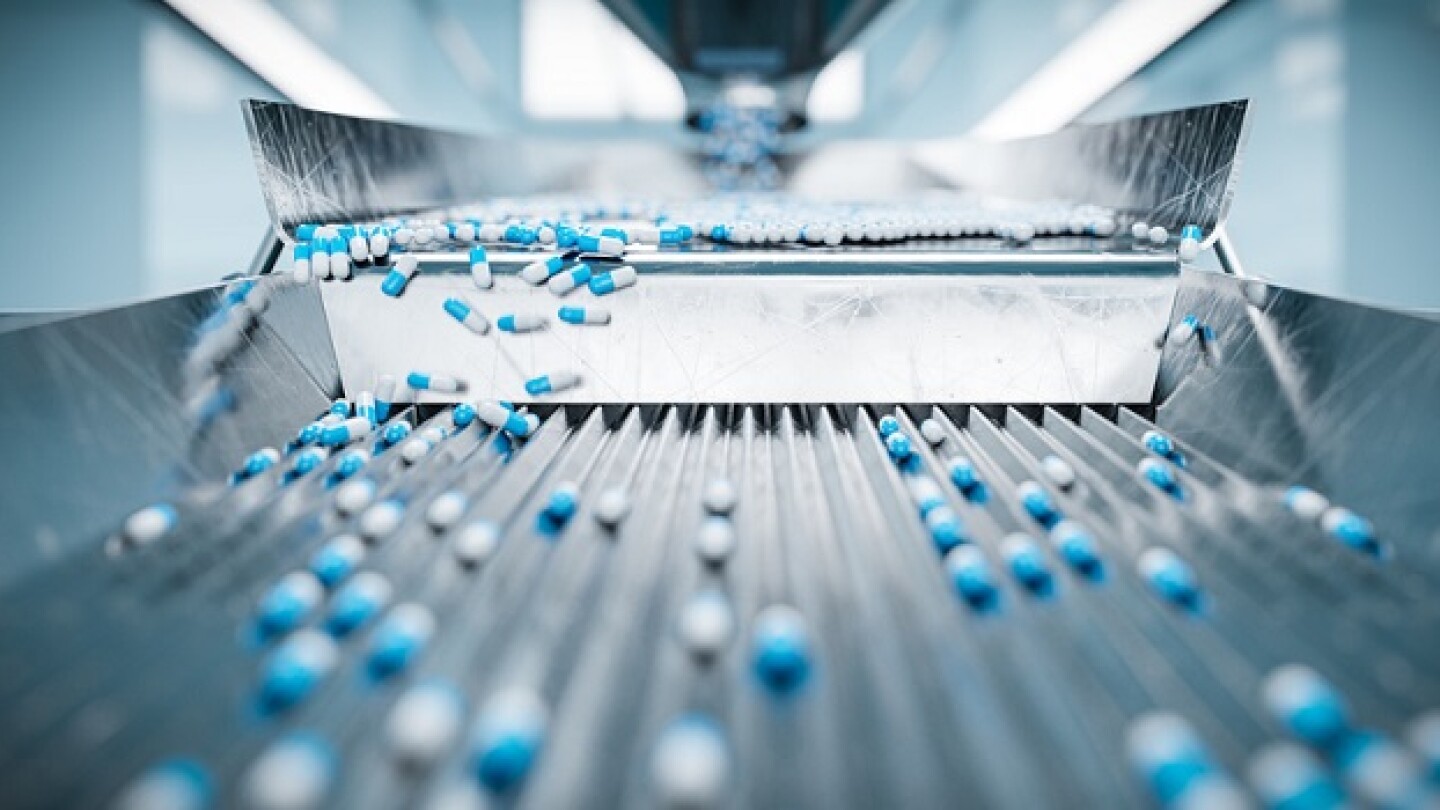 Pictured: Blue and white pills on a metal conveyer belt