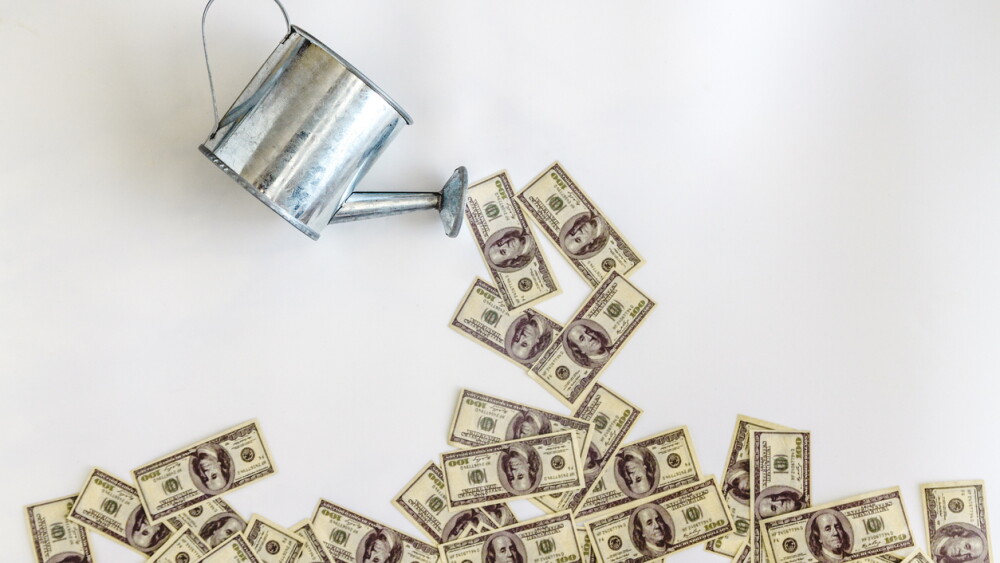 pour-watered from the watering can banknotes dollars on a white background. Concept, investment, start-up business, startup, income growth.