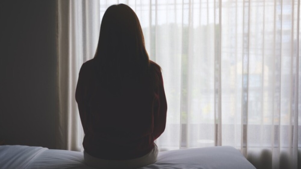 Pictured: Woman sitting on bed alone/iStock, Farkn