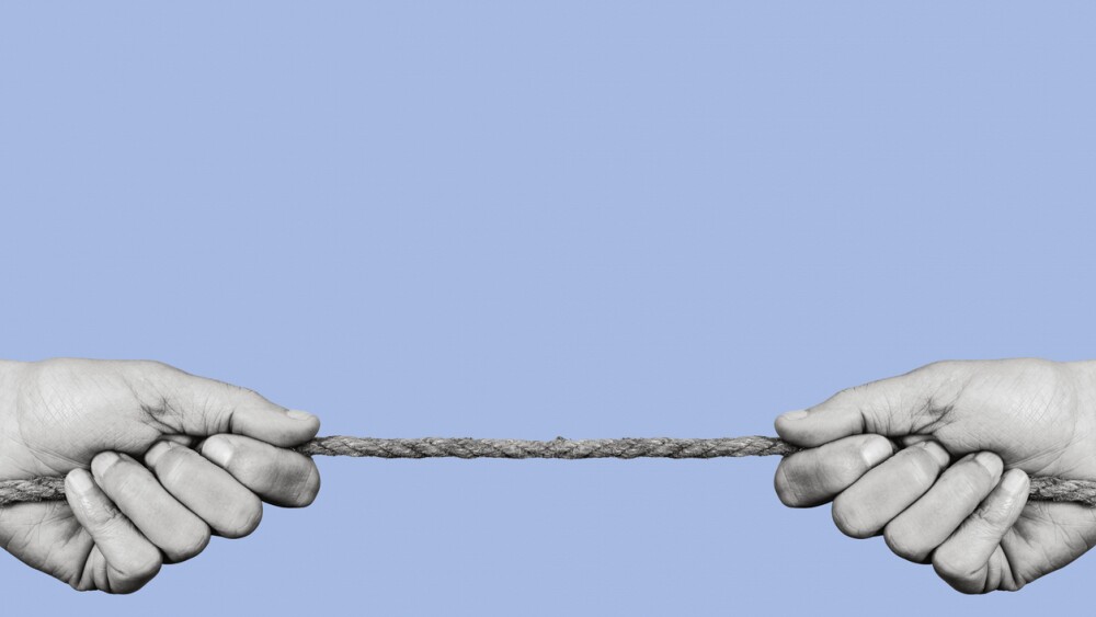 man pulling each of the opposite ends of a rope in black and white, on a blue background with some blank space on top