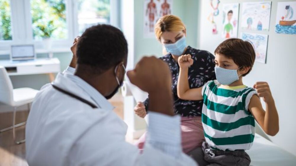 A child flexes his arms for a doctor in a clinic a