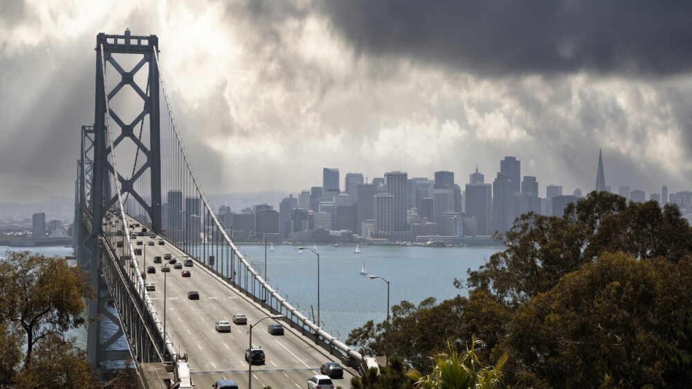 View of traffic on the Bay Bridge with downtown San Francisco and stormy sky in background
