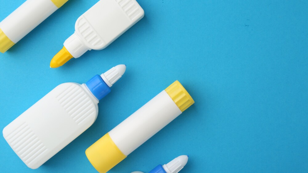 Different types of glue on light blue background, flat lay.  