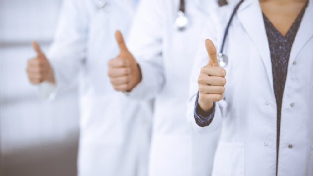 Pictured: Three doctors holding their thumbs up/iS