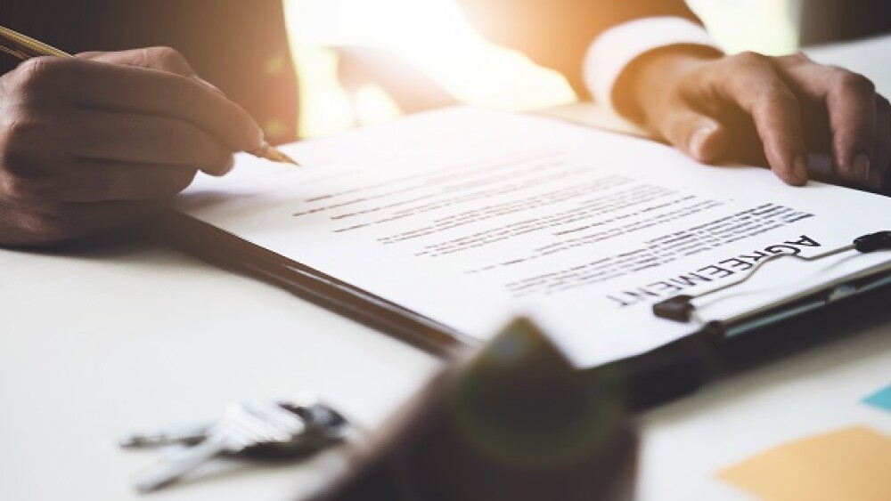 Close up of Businessman pointing and signing agreement contract for buying house. Bank manager and real estate concept.