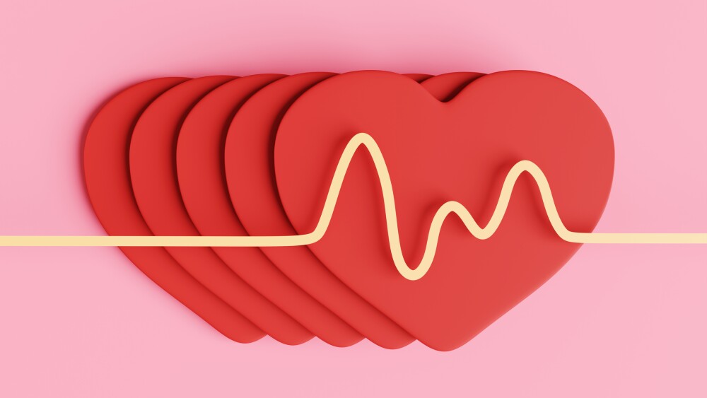 Yellow diagram of pulses on a stack of red paper hearts. Illustration of the concept of healthy lifestyles and cardiovascular related diseases
