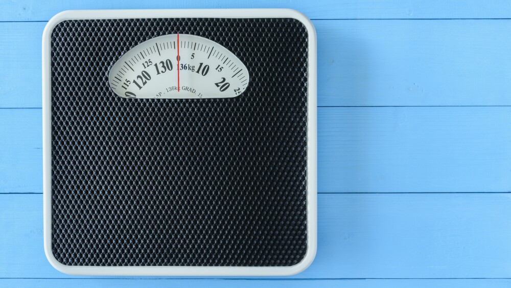 Mechanical weight scale, body mass control concept : Bathroom scale on pale blue wood background. Analog scale operated with spring that pressure is calibrated to translate tension into a mass readout.