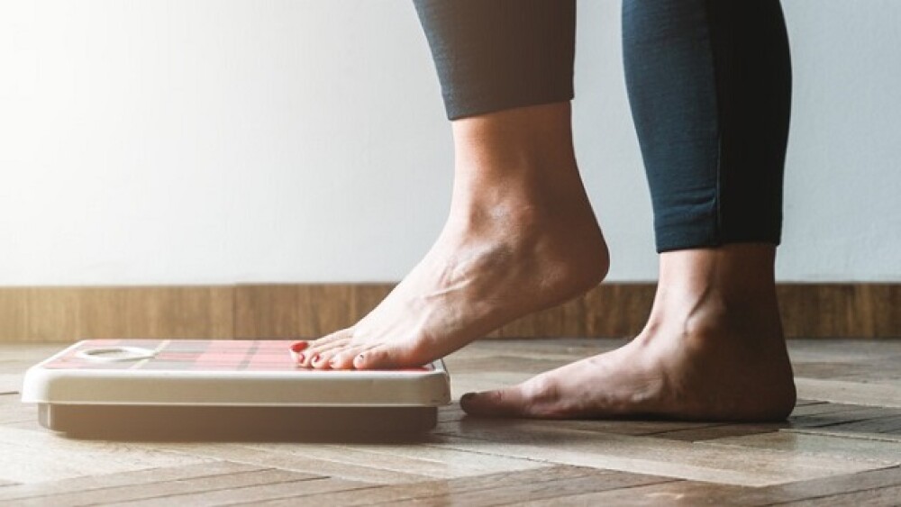 Pictured: Woman stepping onto scale/Courtesy Getty