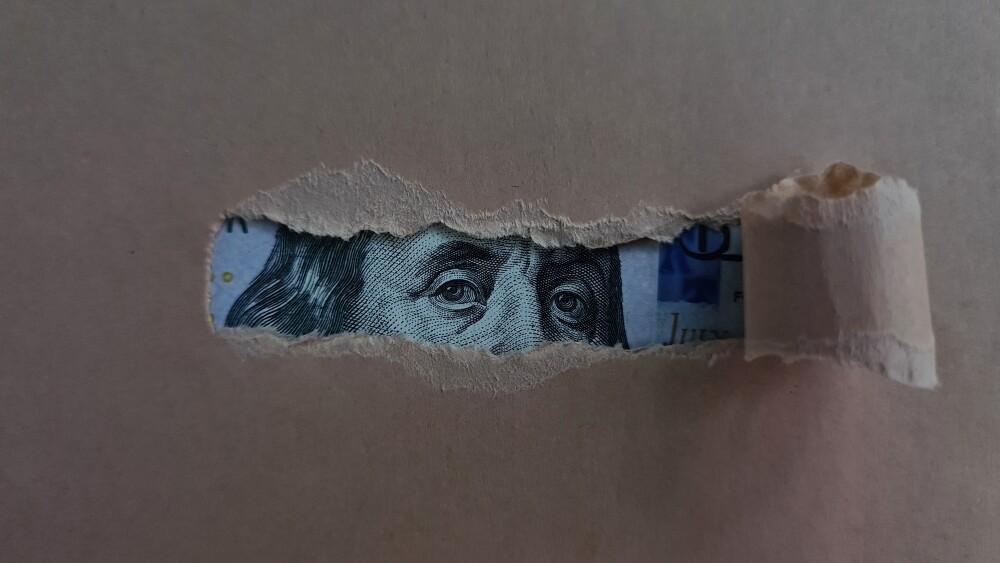 Paper torn and revealing dollar bill. Financial investment and cash income