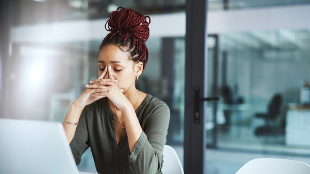 Shot of a young businesswoman looking stressed out while working in an office