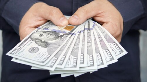 male hands with wrist watch is considered American dollars. Hands holding dollar cash. 1000 dollars in 100 bills in a man's hand close-up on a dark background. hundred
