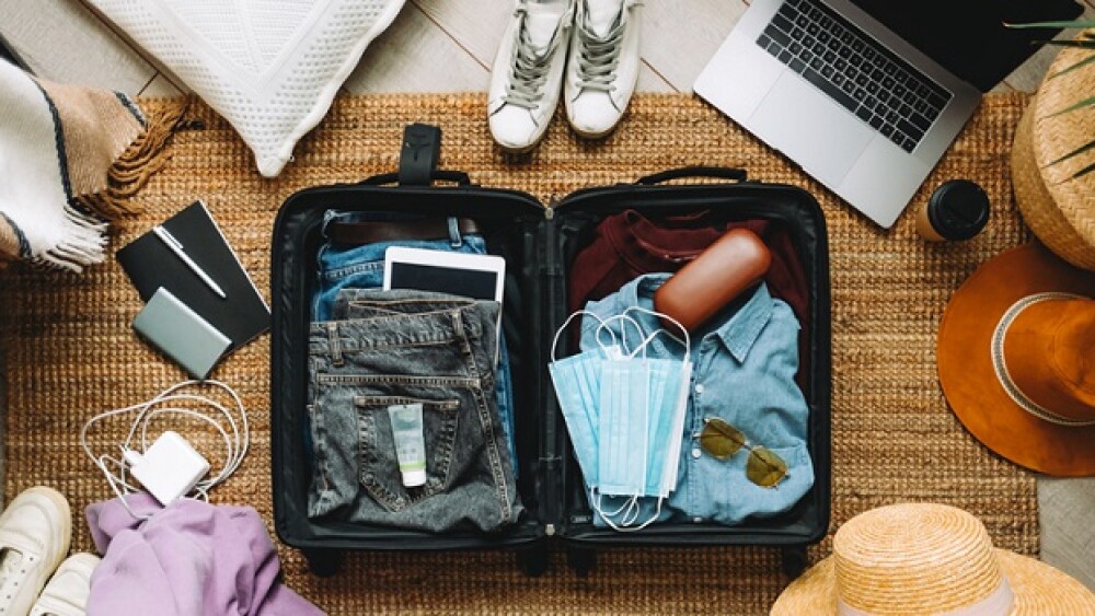 Packing suitcase for travel vacation in new normal, top view.