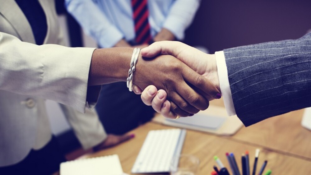 Pictured: Two business people shaking hands / iSto