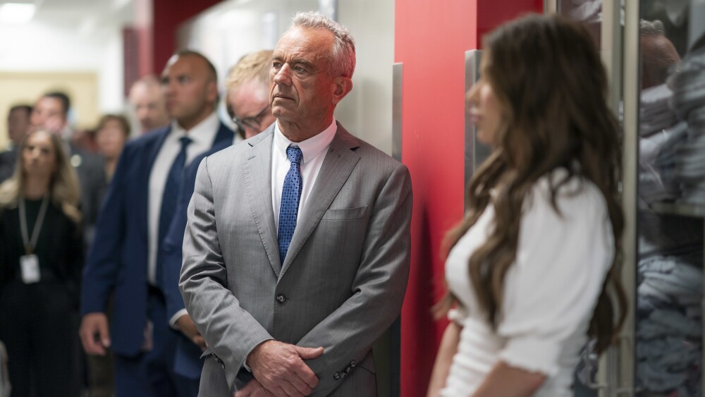 HHS Secretary Robert F Kennedy Jr standing wearing a gray suit with his arms crossed