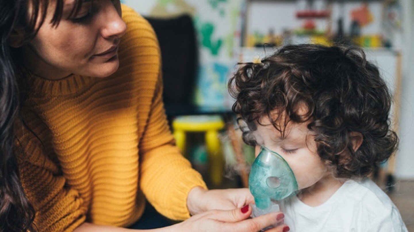 Mother helps her little boy to makes inhalation at home