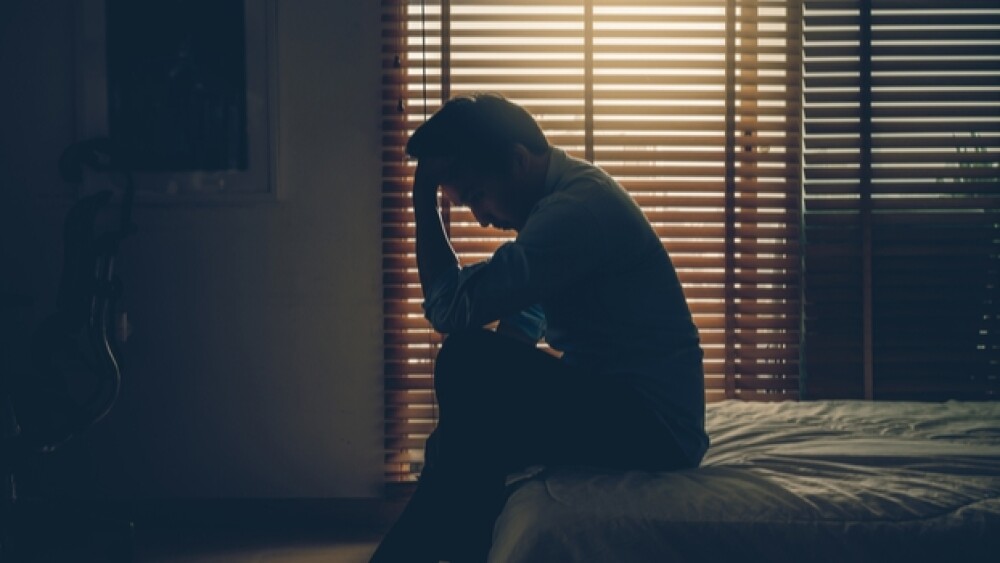 A man sits with head in hands/Courtesy of Shutters