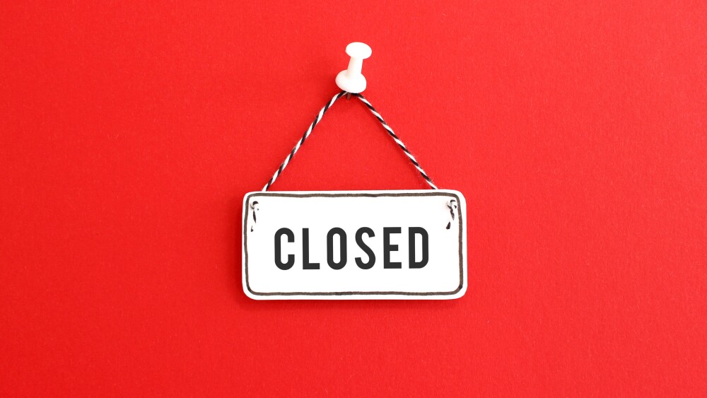 Handmade signboard with Closed inscription and striped rope hanging on pin on bright red background