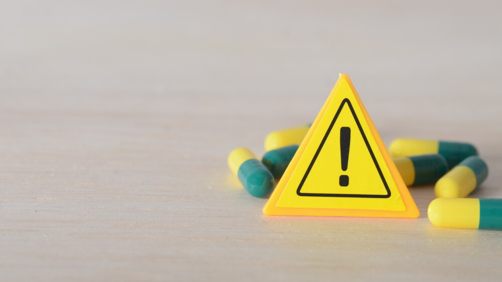 Medication Warning: Yellow Caution Sign with Scattered Capsules