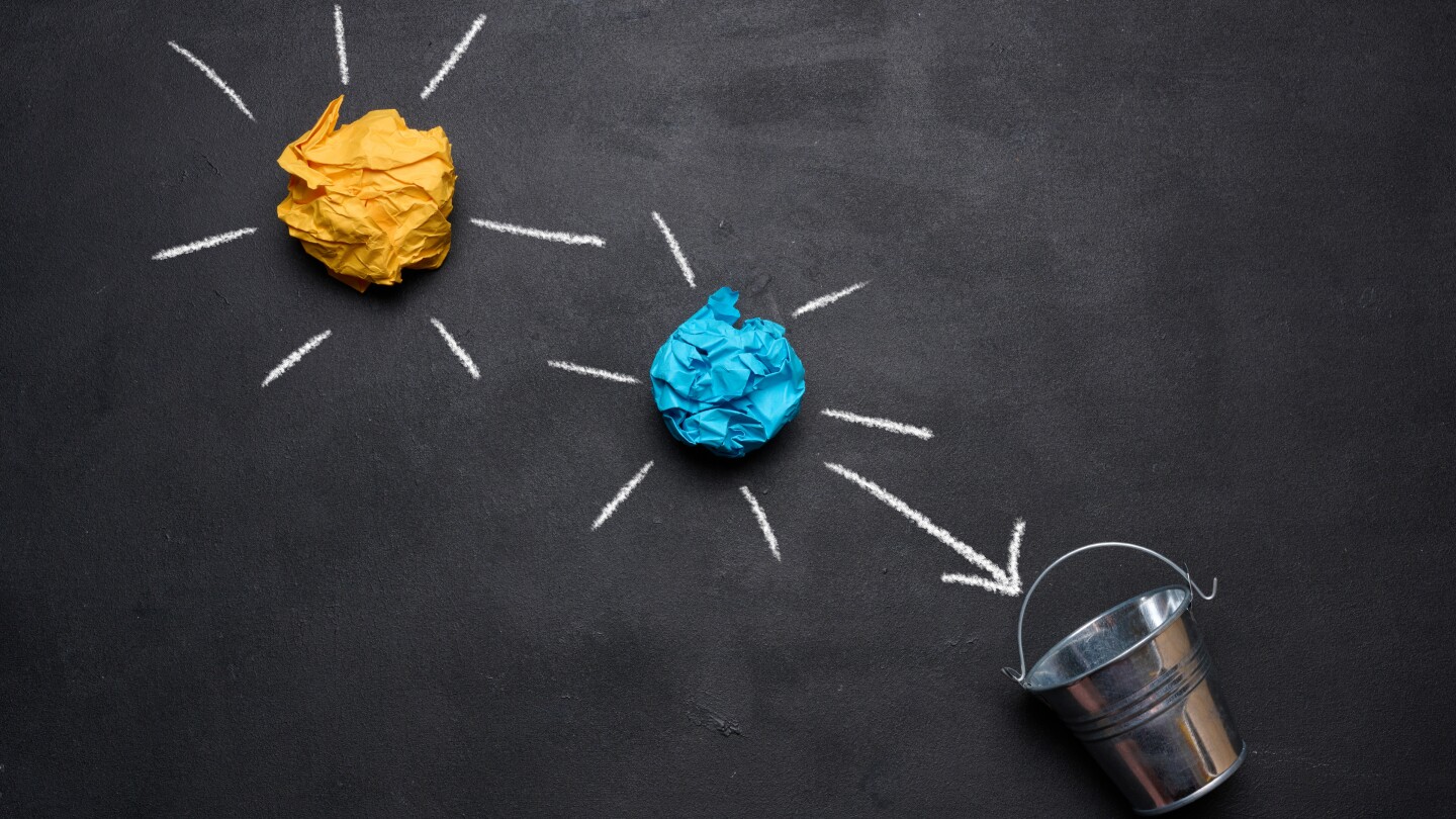 Crumpled paper balls fly into a miniature bucket, the concept of searching for new ideas