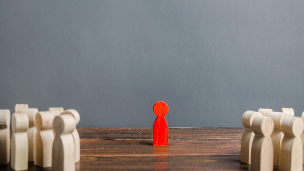 red figurine of a man stands aside from the crowd of people. Asociality, sociopathy. Rejected from society, lonely. Development of leadership and social qualities. Infected, fear and misunderstanding.