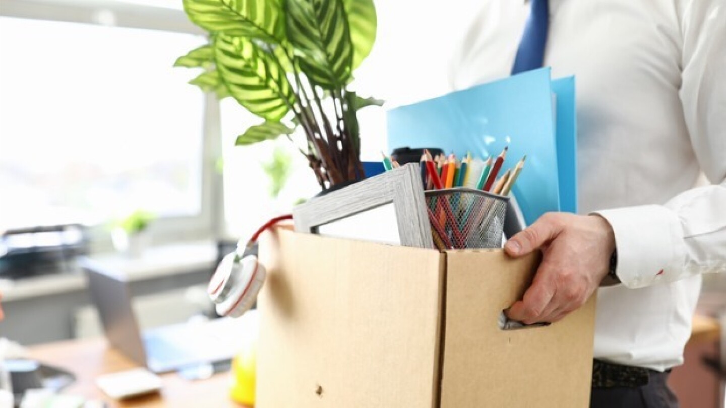 Pictured: Man carrying a box of his office items after being laid off