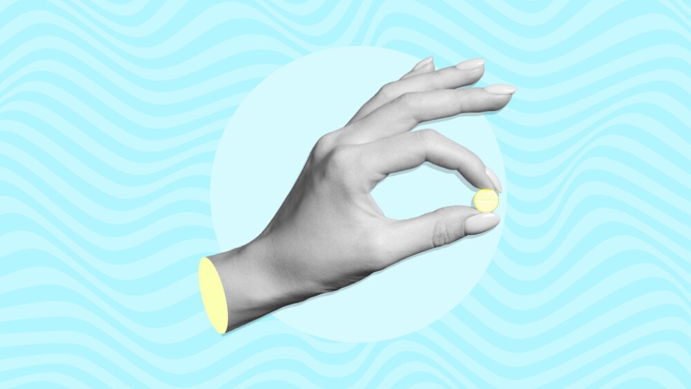 Hand holding a pill against psychedelic background