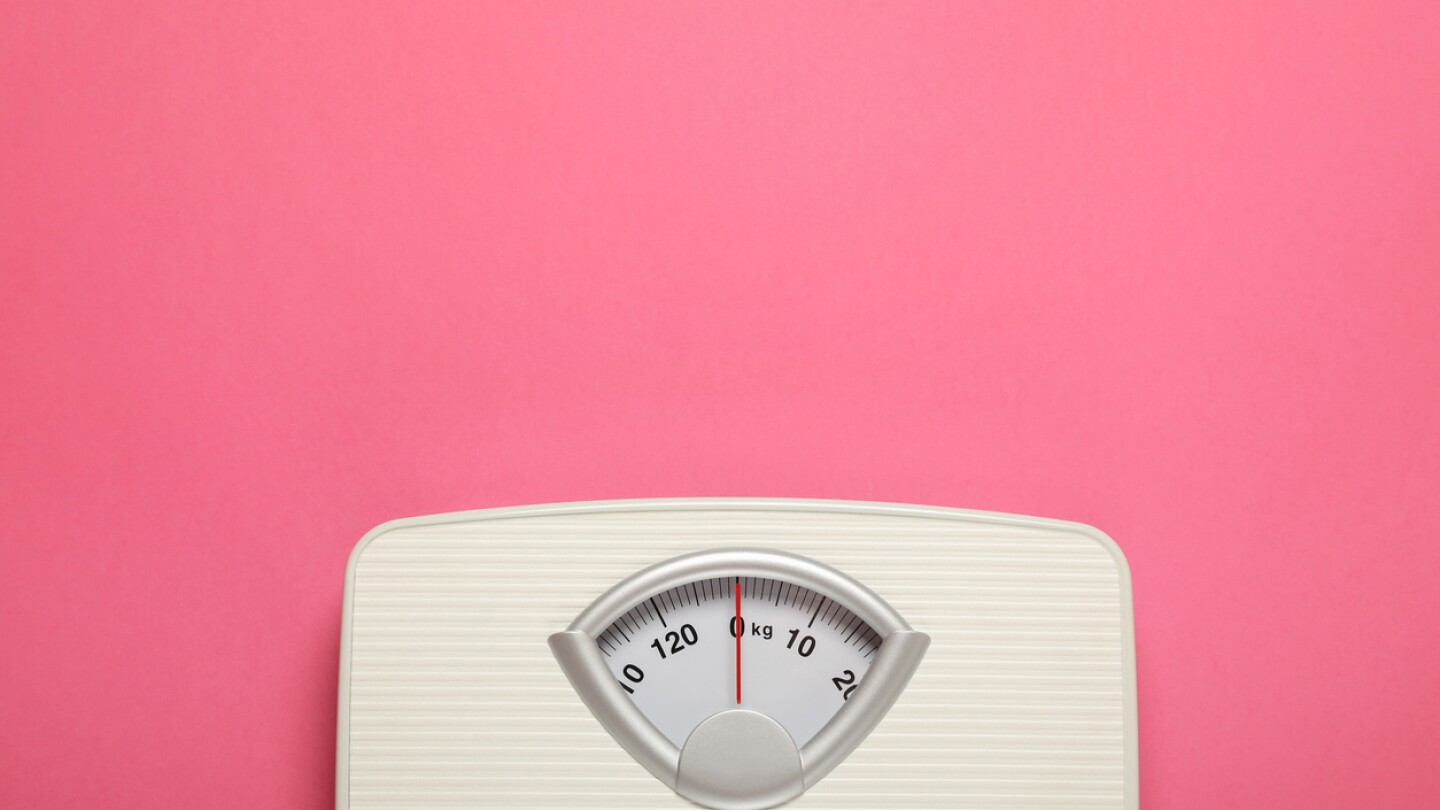 Weigh scales on pink background, top view with space for text. Overweight concept
