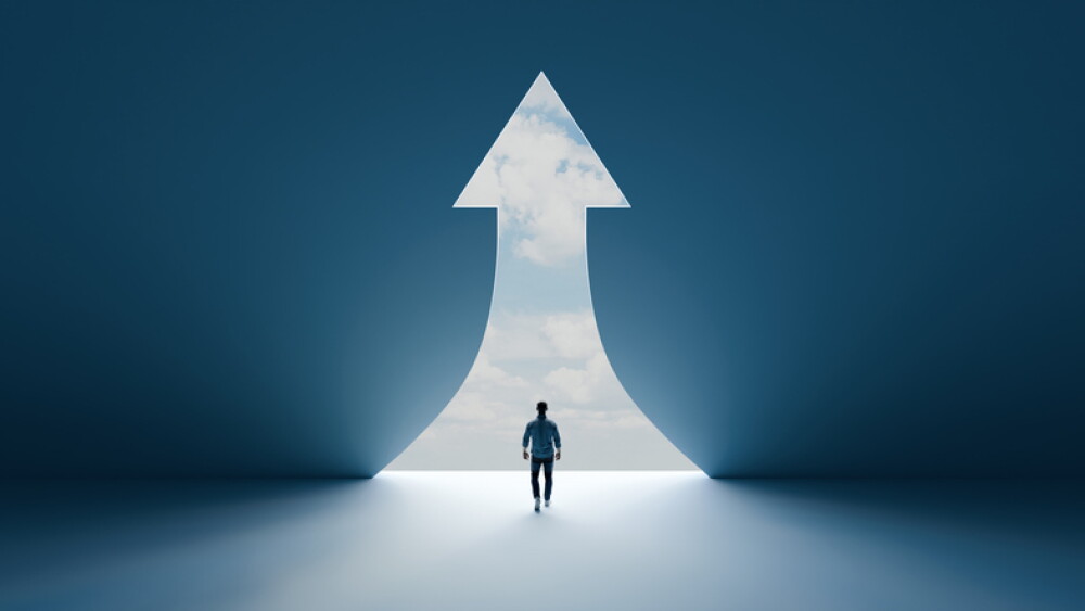 Man walking through a glowing upward arrow shaped doorway with light streaming in from the sky outside, hope, success, 3d render