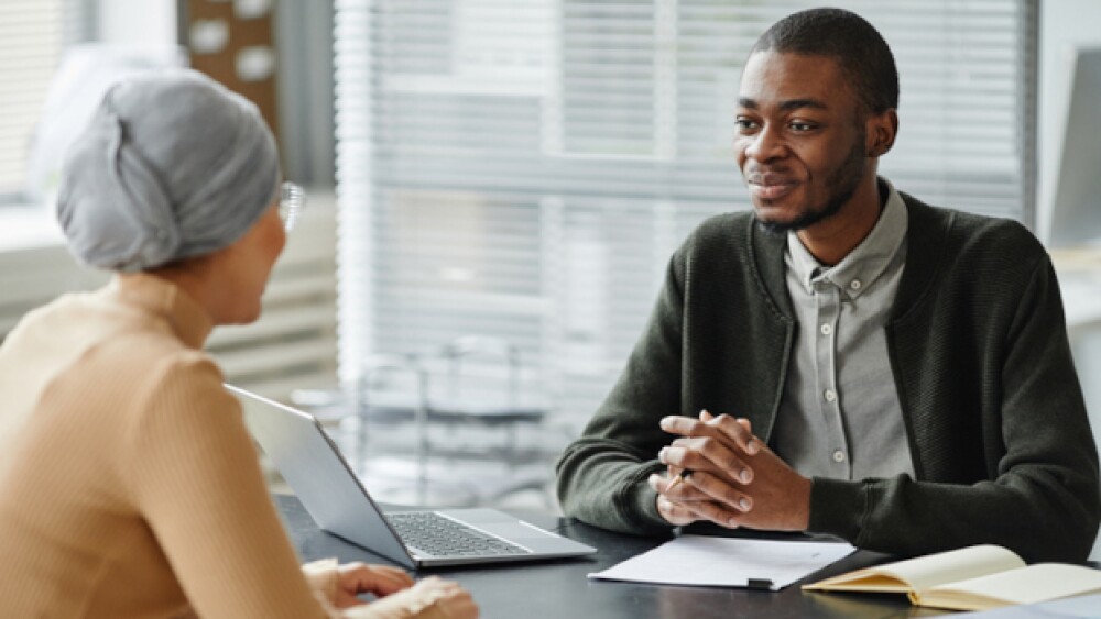 Pictured: Two people sitting at a table talking to